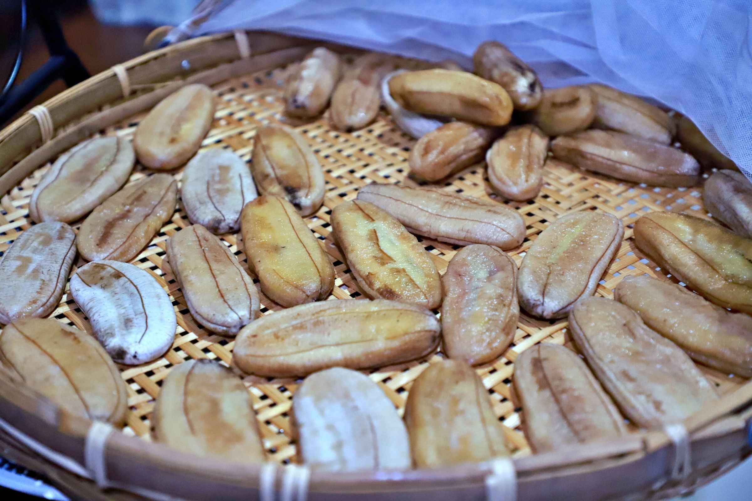 Sun-dried whole bananas arranged in a woven bamboo tray
