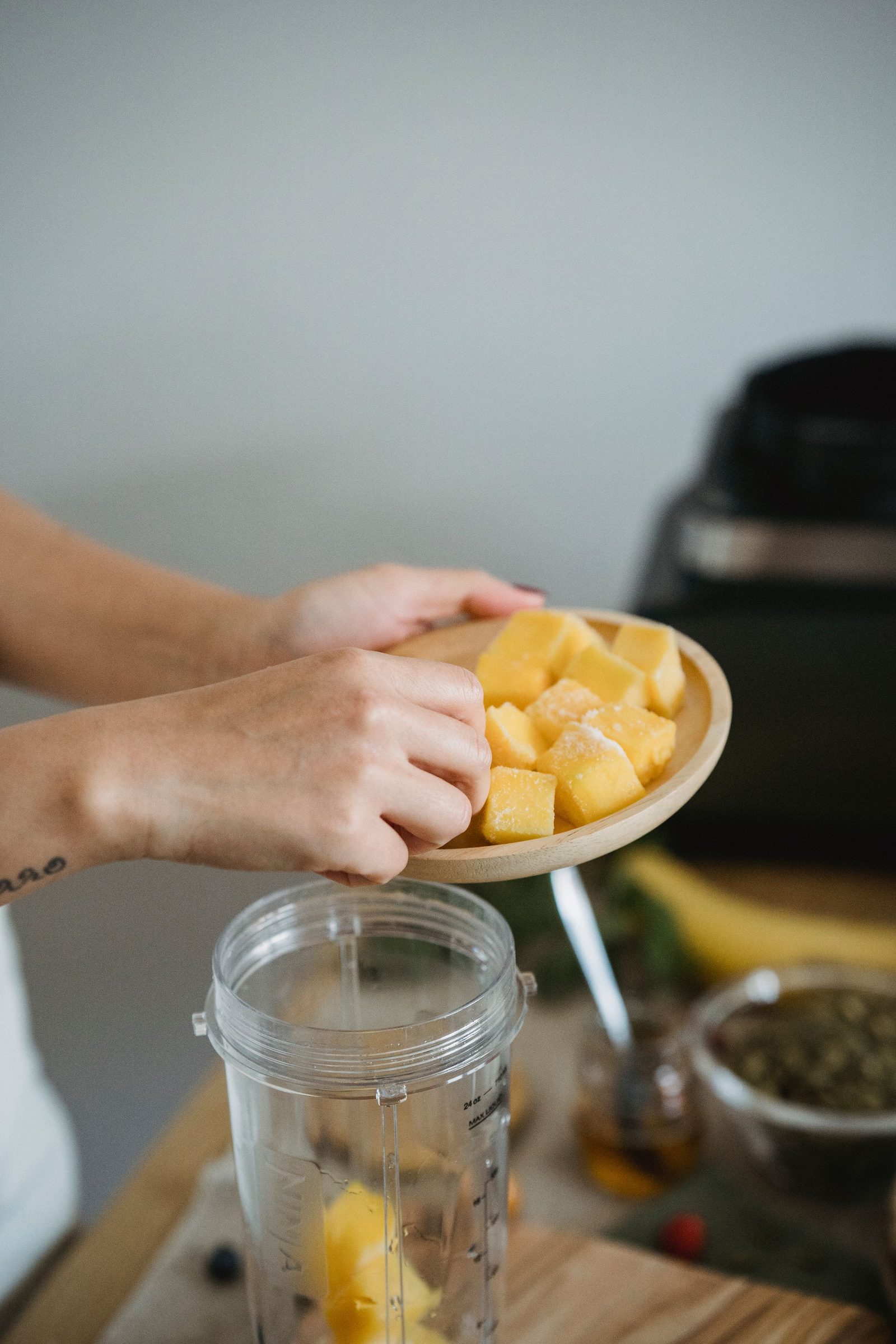Hands plating frost-dusted frozen mango cubes