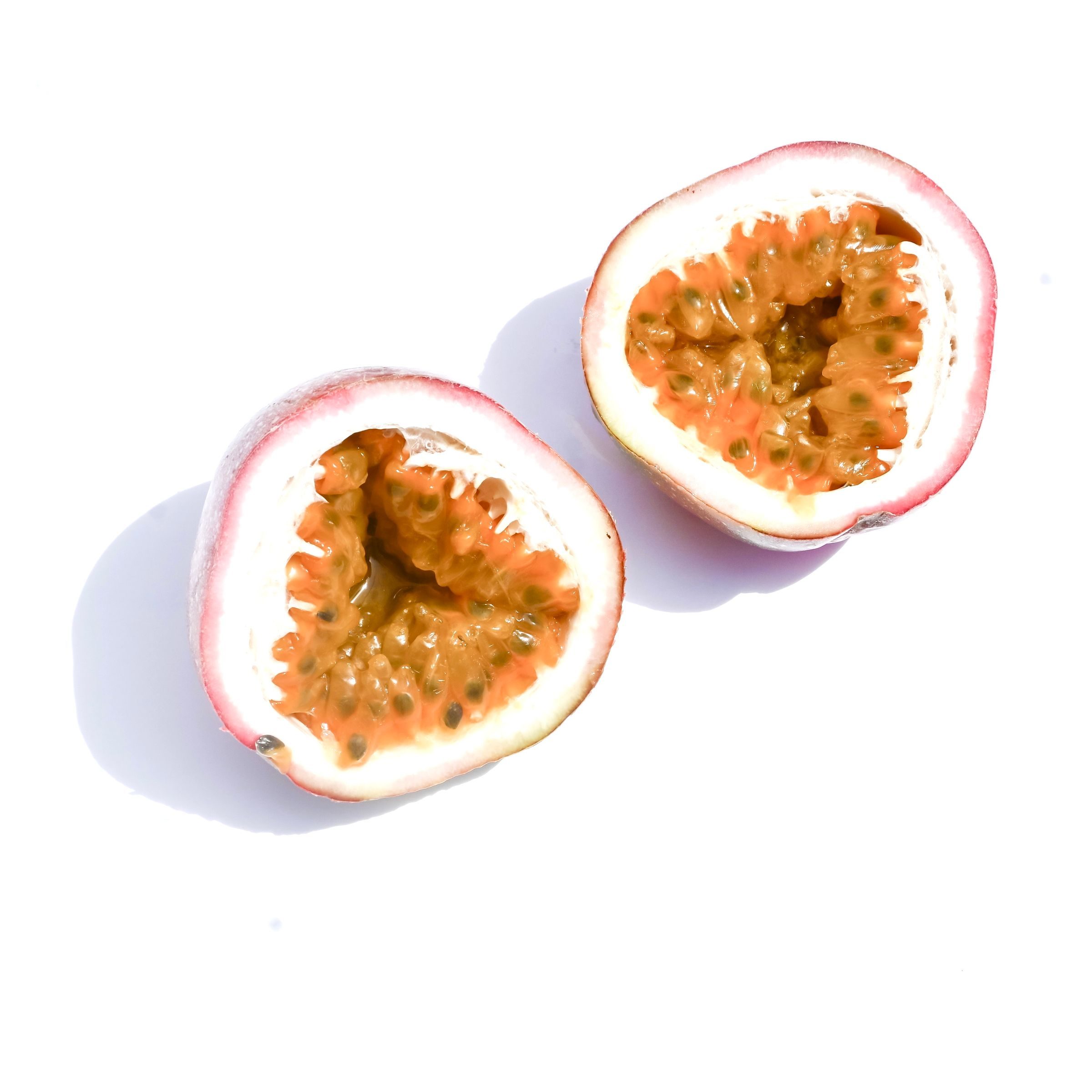 Passion fruit halves showing pulp and seeds on white