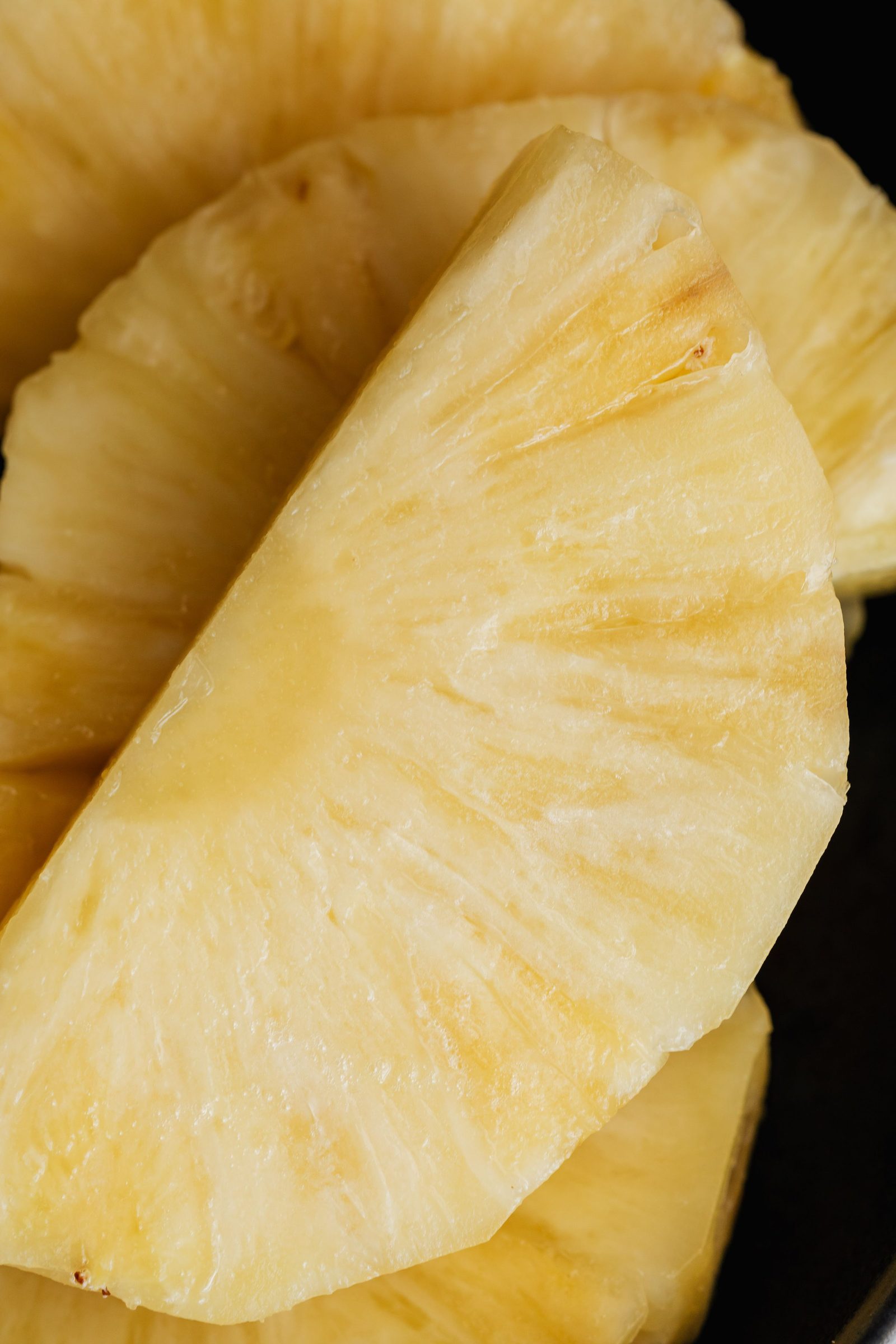 Fresh-cut pineapple slices in close-up on a dark background